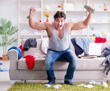 Genç adam dağınık bir odada çalışıyor.