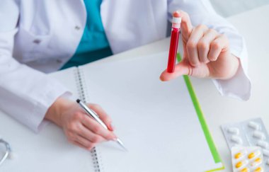 Doktor tıp konseptinde kan tüpünü inceliyor.