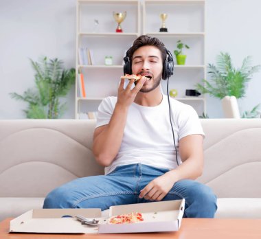 Pizza yiyen adam evde yemek yiyor, dinleniyor.