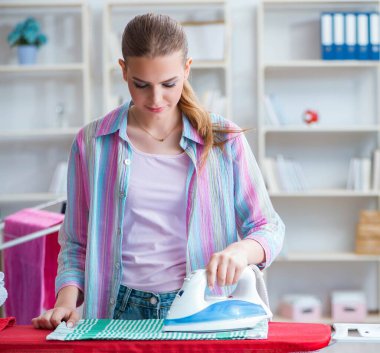 Mutlu ev hanımı evde ütü yapıyor.