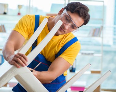 Mobilya tamircisi sandalyeyi tamir etmeye çalışıyor.