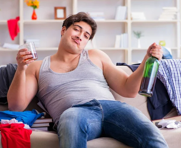 Dağınık bir odada alkol alan genç bir öğrenci.
