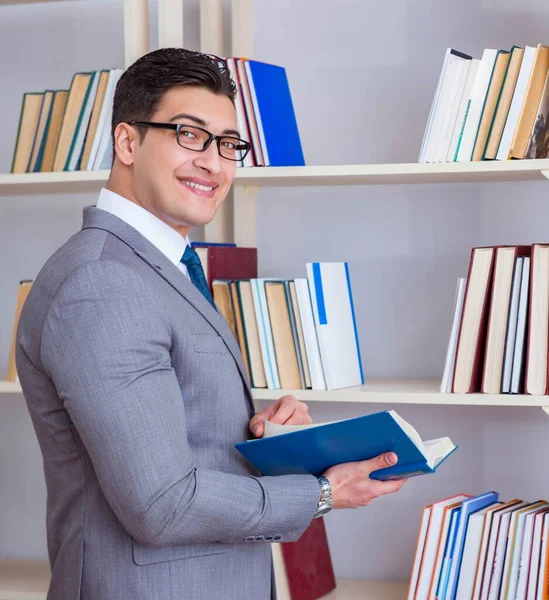 İşadamı öğrenci kütüphanede bir kitap okuyor.