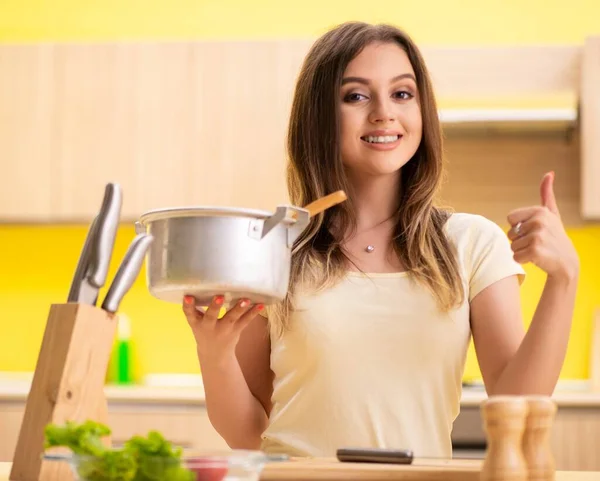 Jovem mulher cozinhando sopa na cozinha em casa — Fotografia de Stock