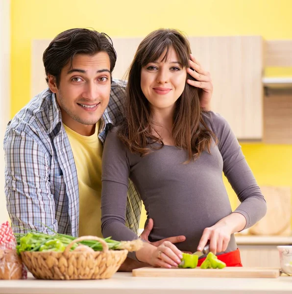 Man och gravid kvinna tillagar sallad i köket — Stockfoto