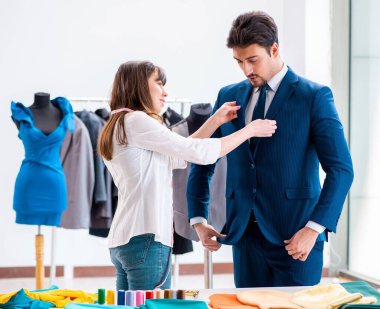 Profesyonel terzi resmi kıyafet için ölçü alıyor.