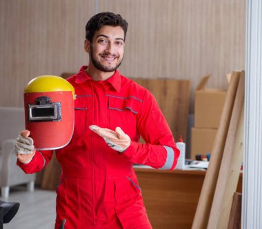 Kaynak tabancası elektrot ve kask takan genç bir tamirci.