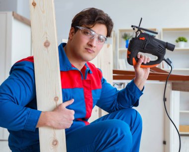 Genç marangoz ahşap kalaslarla çalışıyor.