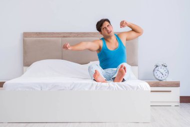 Genç adam yatakta uyanıyor.