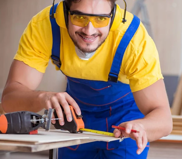 El joven carpintero reparador trabaja cortando madera en forma circular. — Foto de Stock