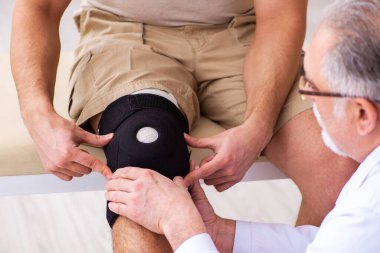 Deneyimli doktor travmatolog genç erkek hastayı muayene ediyor.