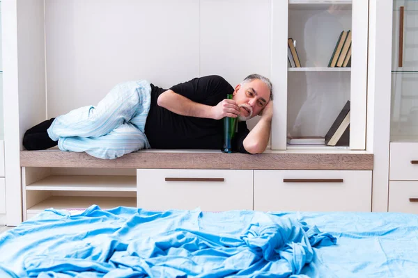 Old man drinking wine in the bedroom — Stock Photo, Image