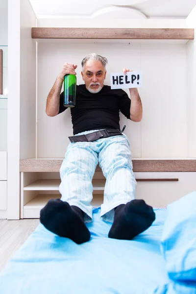 Old man drinking wine in the bedroom — Stock Photo, Image