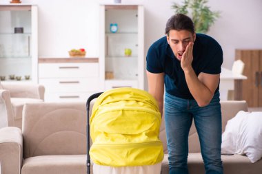 Genç baba yeni doğan bebeğe bakıyor.