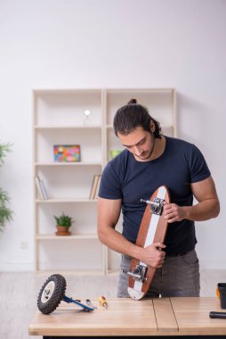 Kaykay tamir eden genç bir erkek tamirci.