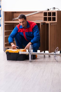 Genç yakışıklı erkek marangoz içeride çalışıyor.