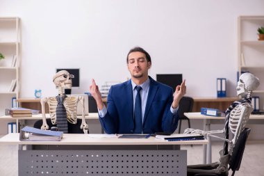Ofiste iskeletleri olan genç bir erkek çalışan.
