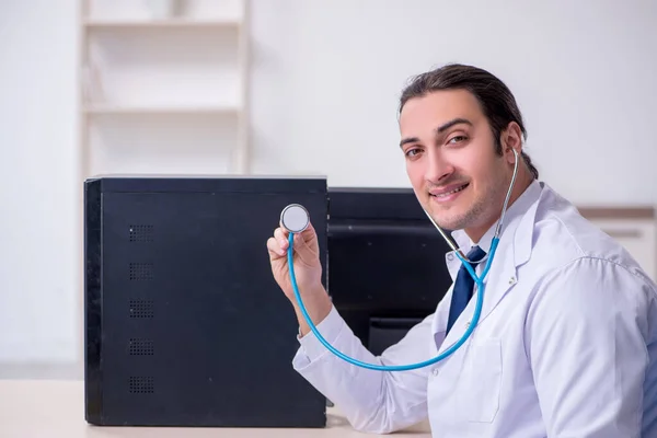 Giovane medico di sesso maschile con stetoscopio riparazione computer — Foto Stock