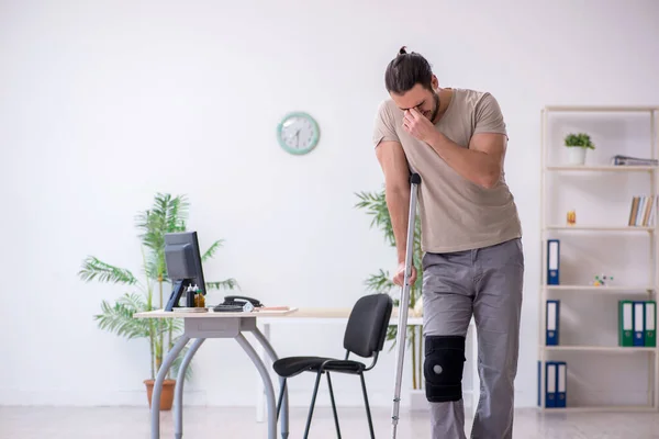 Joven pierna herido hombre con muletas — Foto de Stock