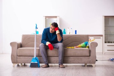 Genç adam evde ev işi yapıyor.