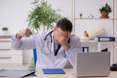 Klinikte çalışan genç erkek doktor.