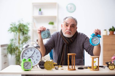 Atölyede çalışan yaşlı bir erkek saatçi.