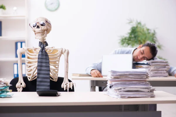 Giovane dipendente maschio e scheletro in ufficio — Foto Stock