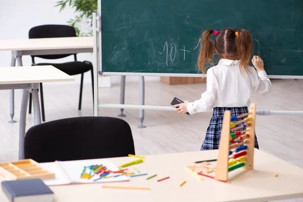 Liten jente foran tavla i klasserommet. – stockfoto