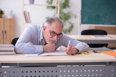 Sınıftaki yaşlı erkek öğretmen.