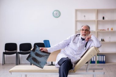 Klinikte çalışan yaşlı erkek doktor.