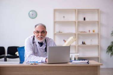 Klinikte çalışan yaşlı erkek doktor.
