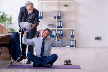 İki çalışan işyerinde fiziksel egzersiz yapıyor.