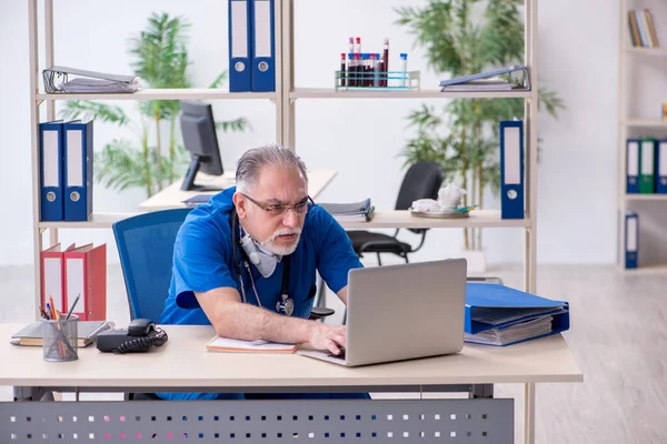 Klinikte çalışan yaşlı erkek doktor. — Stok fotoğraf