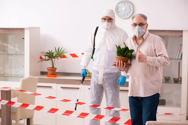 Joven desinfectante masculino y anciano en interiores — Foto de Stock