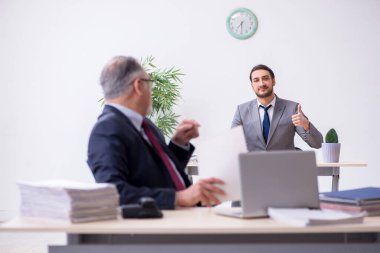 Eski patron ve genç asistanı ofiste çalışıyor.