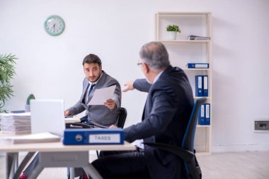 Eski patron ve genç asistanı ofiste çalışıyor.