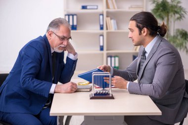 Masada iki iş adamı ve meditasyon topu var.