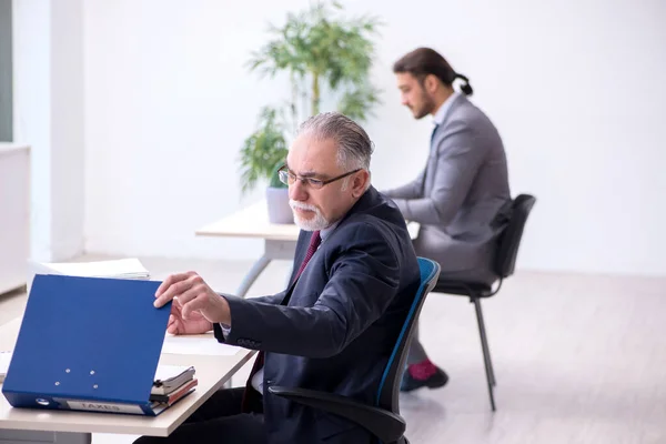 Vecchio capo e il suo giovane assistente che lavorano in ufficio — Foto Stock