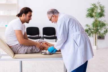 Yaralı adam ilk yardım konseptinde yaşlı doktoru ziyaret ediyor.