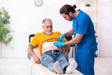 Yaşlı adam genç erkek doktoru ziyaret ediyor.