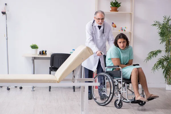 Молодий пацієнт у інвалідному кріслі та досвідчений лікар травматолог — стокове фото
