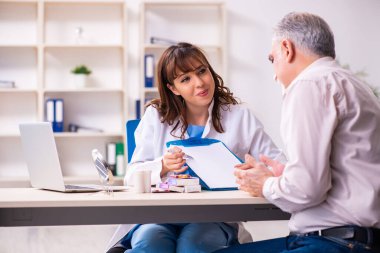 Yaşlı adam estetik ameliyat için genç bayan doktoru ziyaret ediyor.