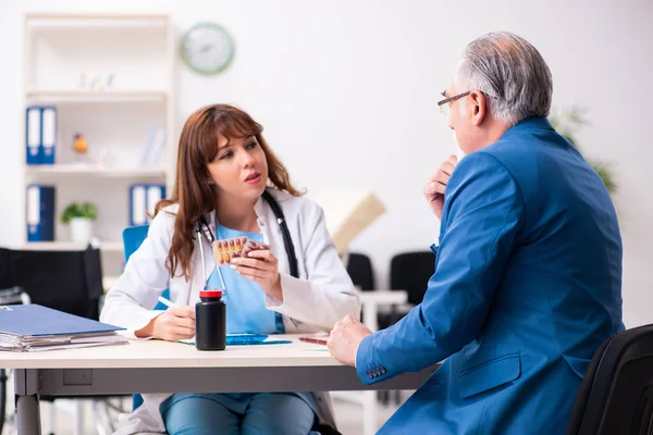 Oude zakenman bezoekt jonge vrouwelijke arts — Stockfoto