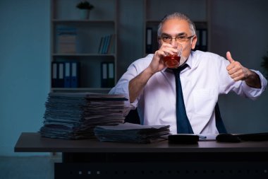 Eski erkek çalışan ofiste geç saatlere kadar çalışıyor.