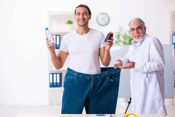 Doctor dietician and happy patient wearing large trousers — Stok fotoğraf