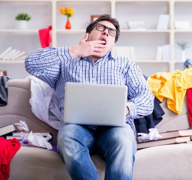 Genç adam dağınık bir odada çalışıyor.