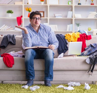 Dağınık odada çalışan genç adam.