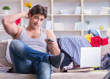 Dağınık odada çalışan genç adam.