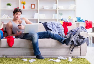 Genç adam dağınık bir odada çalışıyor.