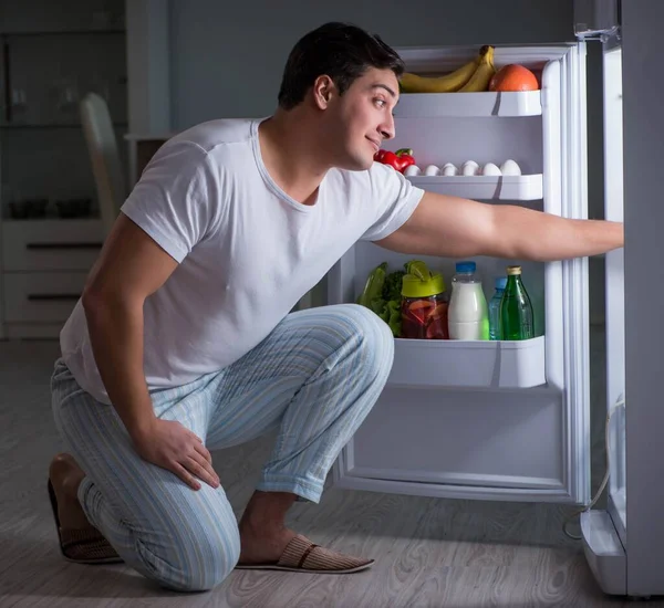 Человек у холодильника ест по ночам — стоковое фото